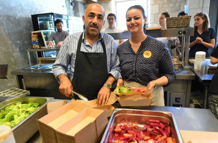 Jawad (g) et Zainab Al-Khajee, couple de journalistes irakiens réfugiés en France, préparent des plats irakiens, le 23 juin 2018 dans le snack de Darwin, un espace associatif sur les bords de la Garonne, à Bordeaux