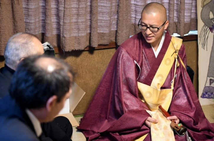 Kaichi Watanabe, un moine bouddhiste (D) s'entretient avec des particuliers lors d'une cérémonie à domicile à Funabashi, une banlieue de Tokyo le 10 novembre 2016
