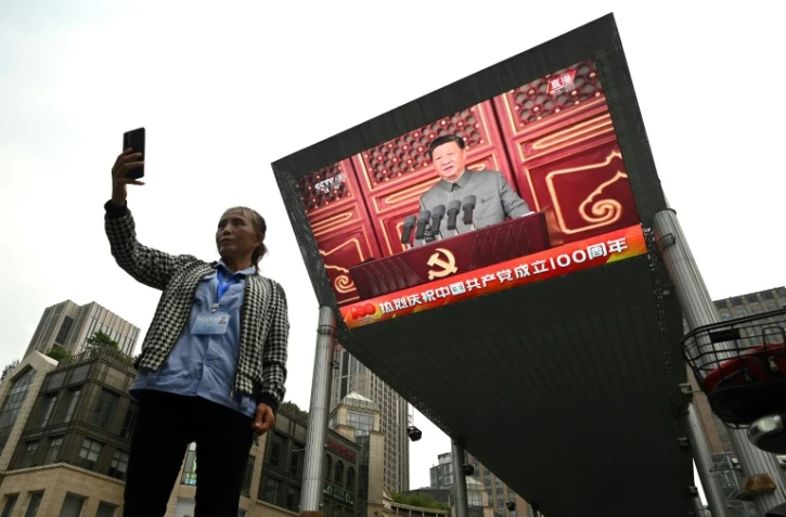 Une femme prend un selfie devant un écran sur lequel est retransmis le discours du président chinois Xi Jinping à l'occasion du centenaire du parti communiste chinois, à Pékin le 1er juillet 2021