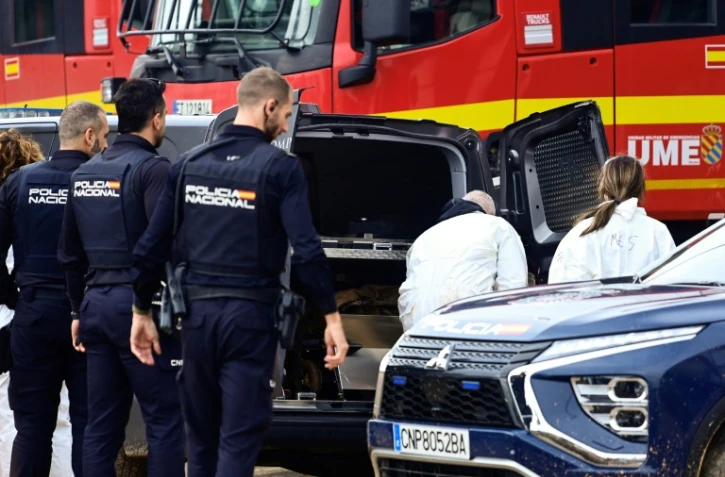 La police se tient devant des équipes médico-légales alors qu'elles chargent une victime dans une camionnette des pompes-funèbres la suite des inondations dévastatrices à Alfafar, dans la région de Valence, dans l'est de l'Espagne, le 4 novembre 2024
