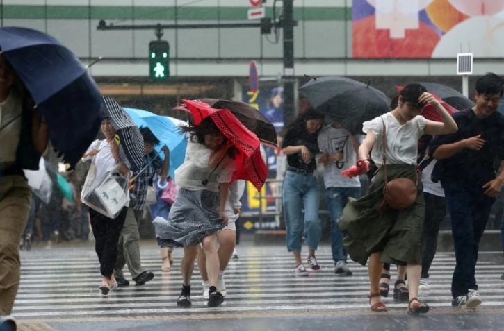 Les passants à Tokyo se protègent de la pluie provoquée par le typhon Jongdari, le 28 juillet 2018