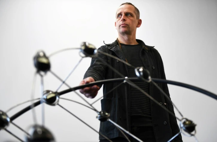 L'artiste de cirque Johann Le Guillerm pose devant l'une de ses sculptures exposées à La Friche de la Belle de Mai, le 20 janvier 2017 à Marseille