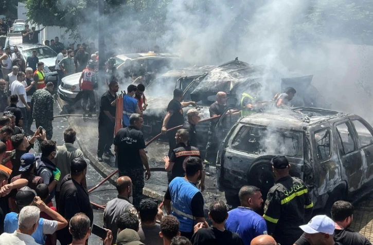 Des secouristes et des habitants sur le site d'une frappe aérienne israélienne qui a touché une voiture à Saïda, le 10 juin 2026 au Liban