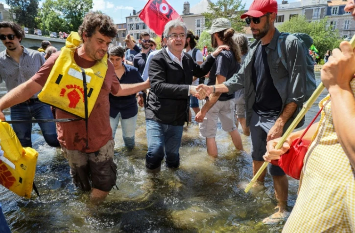 Le leader de la France insoumise (LFI) et chef de la coalition de gauche Nupes (Nouvelle allinace progressiste écologiste et sociale) Jean-Luc Melenchon (centre) serre la main de ses parisans alors qu'il traverse la rivière Clain près du pont de Joubert à Poitiers, sud-ouest de la France, le 2 juin 2022
