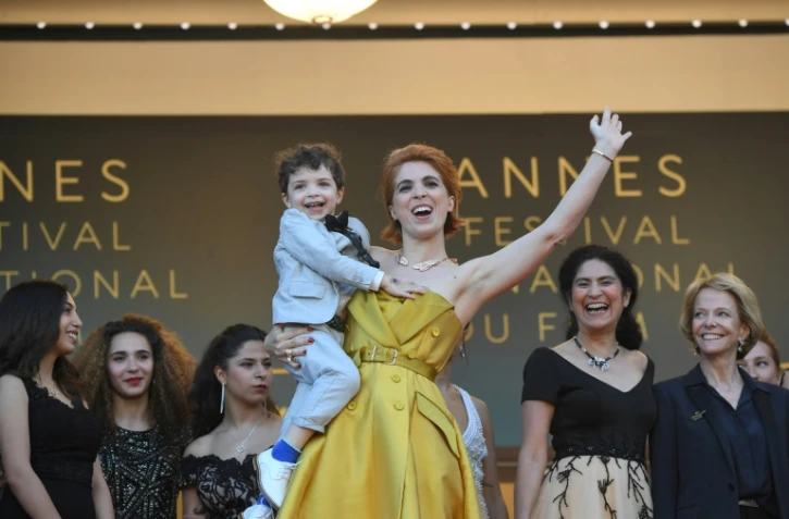La réalisatrice française Eva Husson avec son fils dans les bras, monte les marches du Festival de Cannes pour la projection de son film "Les Filles du Soleil", en compétition, le 12 mai 2018