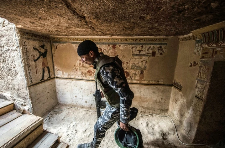 Un membre des forces de sécurité égyptiennes à l'entrée d'une tombe datant de 2.000 ans dévoilée le 5 avril 2019 à Akhmim