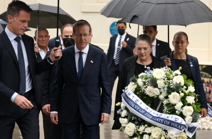 Le président israélien Isaac Herzog (c) et son épouse Michal (2e d) accompagnés par le Premier ministre de Nouvelle-Galles du Sud, Chris Minns (g), déposent une gerbe en hommage aux victimes de l'attaque du 14 décembre 2025 au Bondi Pavilion, à Sydney, le 9 février 2026 en Australie