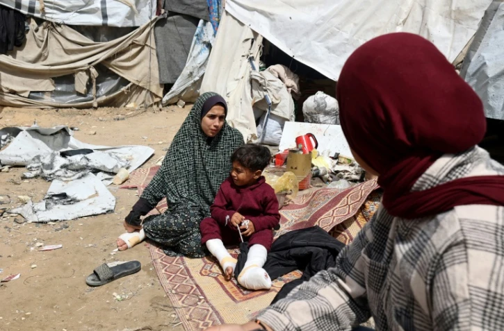 Une famille palestinienne déplacée, dont des membres ont été blessés lors de frappes israéliennes, devant sa tente à Deir el-Balah, dans le centre de la bande de Gaza, le 13 avril 2025