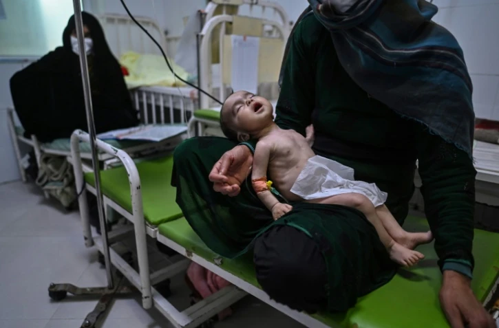 Une mère tient son enfant souffrant de malnutrition, mis sous perfusion dans une clinique de Médecins sans Frontières à Hérat, en Afghanistan, le 22 novembre 2021