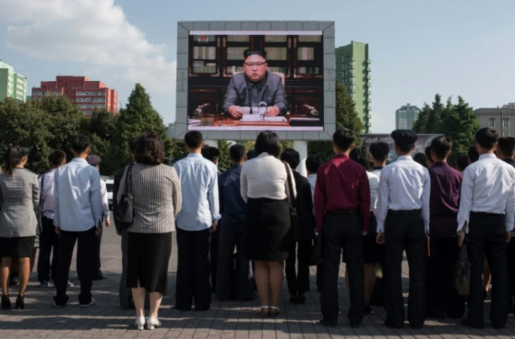 Des spectateurs écoutent la lecture d'une déclaration du dirigeant nord-coréen Kim Jong-Un devant un écran géant installé près de la gare de Pyongyang le 22 septembre 2017.