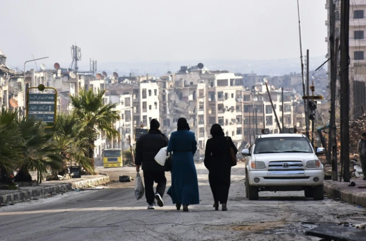 Des habitants marchent dans une rue de l'ancien quartier rebelle de Zebdiye, le 23 décembre 2016 à Alep, en Syrie