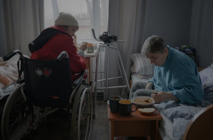 Deux femmes âgées prennent leur repas dans leur chambre, dans un refuge pour seniors à Kharkiv, en Ukraine, le 26 mars 2025