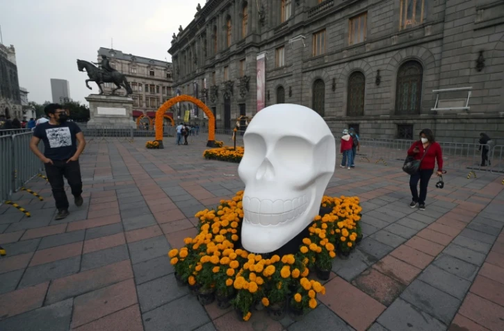 Des passants observent un crâne, qui fait partie d'un hommage rendu aux quelque 300.000 morts du Covid-19 au Mexique, à Mexico le 29 octobre 2021