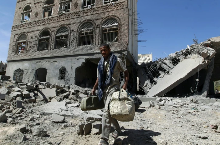 Un homme transporte ses affaires à travers les ruines de bâtiments détruits par la coalition dirigée par l'Arabie saoudite, à Sanaa le 28 octobre 2015
