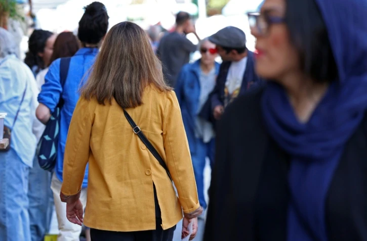 Des passants dont une femme sans voile dans la rue à Téhéran en Iran le 25 avril 2026