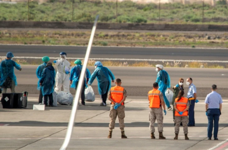 Des passagers espagnols en combinaison de protection, évacués du navire touché par un foyer d'hantavirus, attendent de monter à bord d'un avion à l'aéroport de Tenerife, le 10 mai 2026

