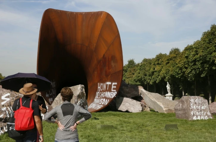Des visiteurs s'arrêtent devant une des  ?uvres de Anish Kapoor vandalisée par des tags antisémites, dans les jardins du Château de Versailles le 11 septembre 2015