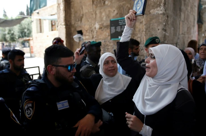 Une palestinienne manifeste et brandit un exemplaire du Coran devant un membre des forces de sécurité israéliennes, à Jérusalem, le 20 juillet 2017