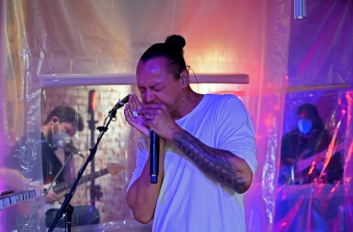 Le Français Frédéric Yonnet, virtuose de l'harmonica, avec sa formation de quatre membres, séparés par des bâches en plastique, joue pour les habitants du quartier de Capitol Hill, le 3 mai 2020 à Washington