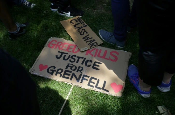 "La cupidité tue", clame cette pancarte sur le sol, lors d'une manifestation le 21 juin 2017 près de la Grenfell Tower de Londres, où au moins 80 personnes ont trouvé la mort dans le gigantesque incendie du 14 juin