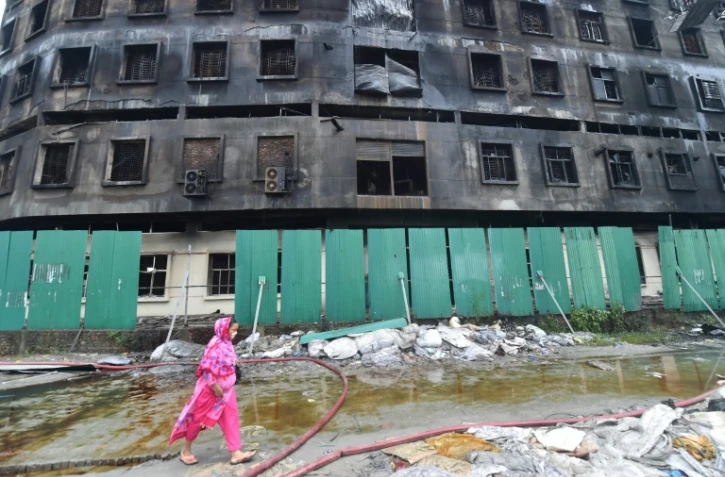 Une femme passe, le 10 juillet 2021, devant la carcasse de l'usine dont l'incendie a fait 52 morts, à Rupganj, dans la banlieue de Dacca