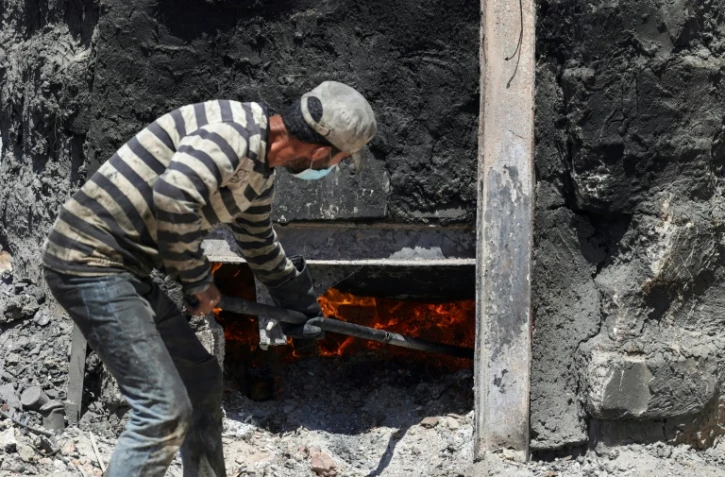 Un ouvrier palestinien allume une cuve contenant une tonne de plastique afin de distiller le pétrole qui le compose, à Jabalia, dans la bande de Gaza, le 23 août 2022