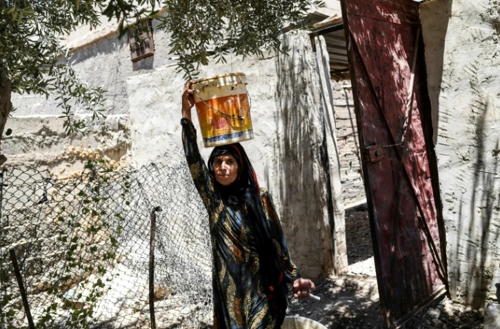 Warda al-Jassem porte de l'eau pour arroser sa vigne, en revenant chez elle à Jazra, banlieue à l'ouest de Raqa, le 15 juillet 2017, cinq semaines après avoir fui les combats contre le groupe EI