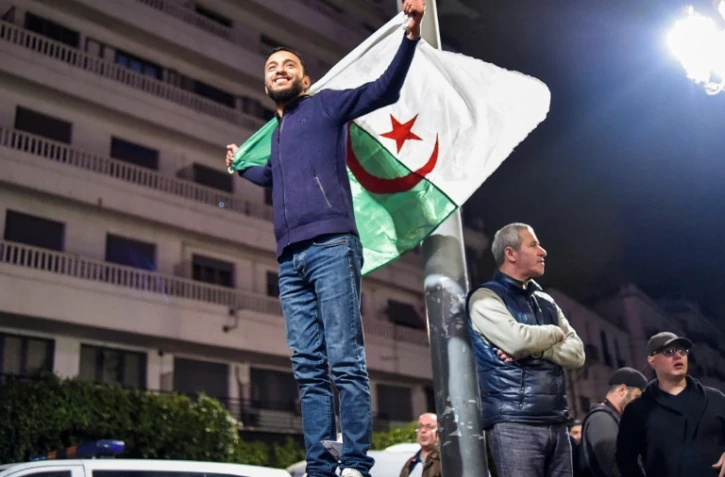 Un Algérien brandit le drapeau national lors de rassemblements dans les rues de la capitale Alger, le 11 mars 2019 au soir