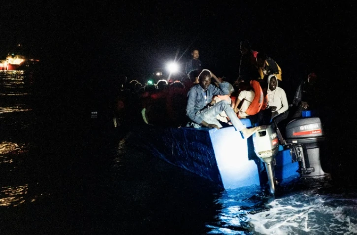 Des migrants s'apprêtent à embarquer sur l'Ocean Viking dans les eaux internationales près de Malte pour être pris en charge par l'association humanitaire SOS Méditerranée en pleine nuit, le 25 octobre 2022