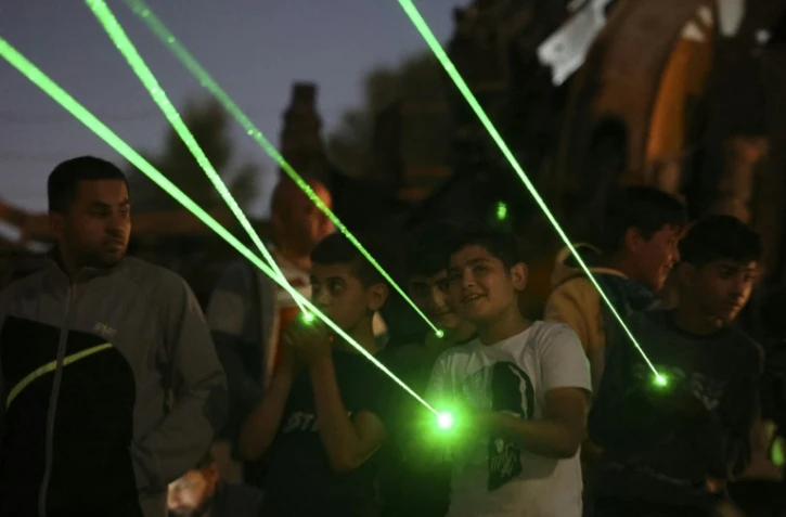Des manifestants palestiniens à Beita en Cisjordanie projettent des rayons lasers verts vers la colonie Eviatar, installée sur une colline, le 23 juin 2021