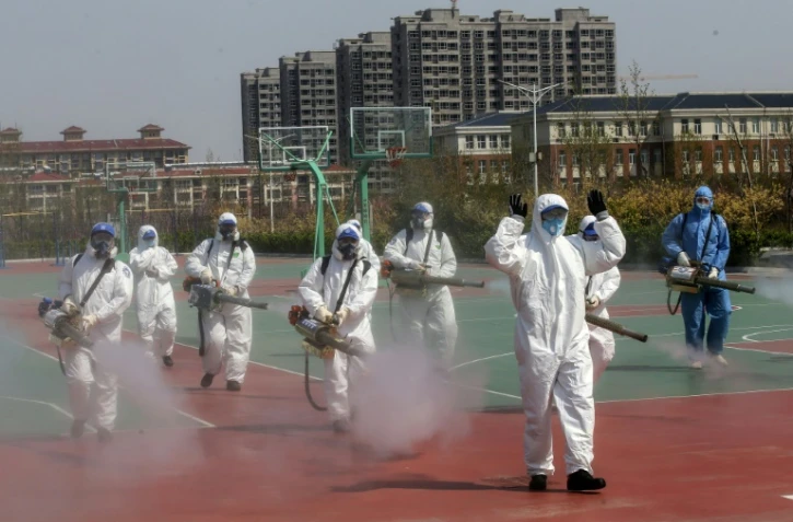 Des bénévoles désinfectent la cour d'une école avant sa réouverture, le 12 avril 2020 à Weifang, dans l'est de la Chine