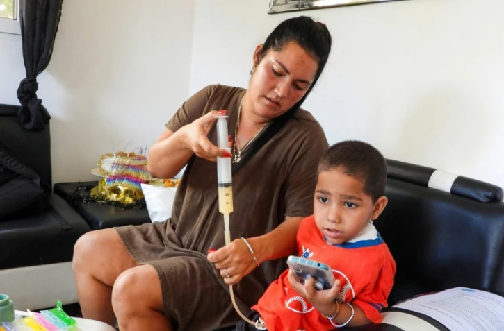 Jessica Rodriguez administre un médicament à son fils Luis Angelo à leur domicile du quartier de Santa Fe à La Havane, le 2 juillet 2025 à Cuba