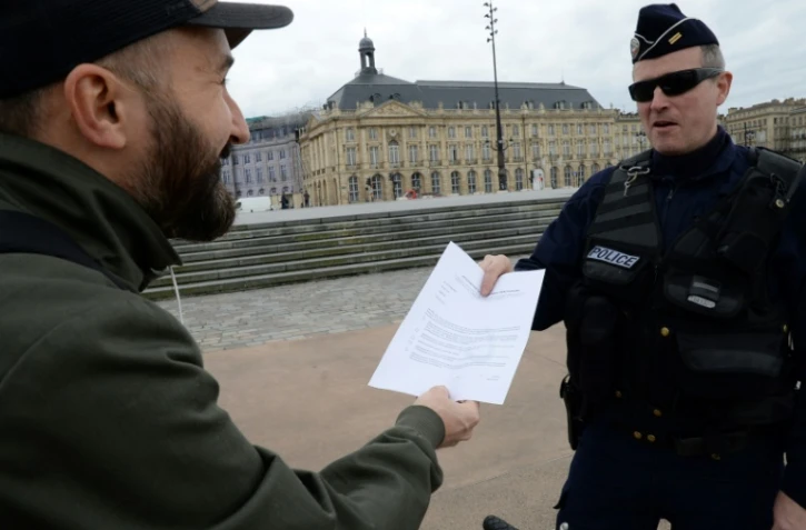 Un policier contrôle le laisser-passer d'un habitant à Bordeaux, le 17 mars 2020. Le confinement de la population est un moyen important de lutte contre la propagation de l'épidémie de coronavius