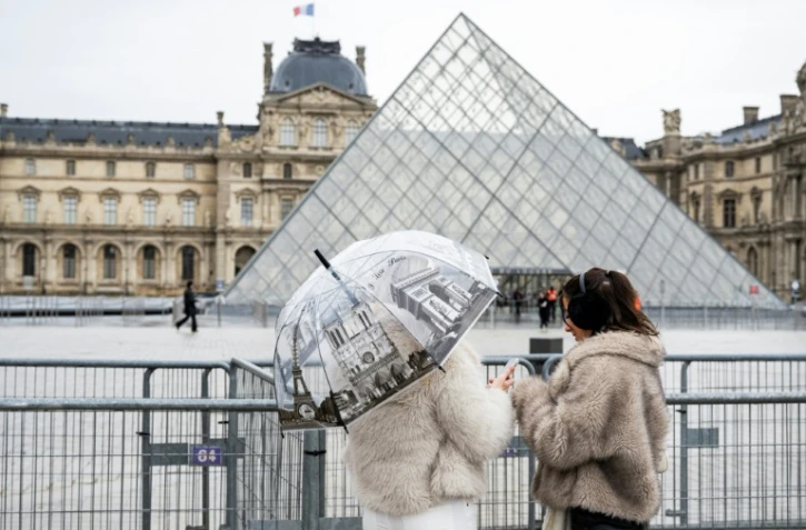 Des visiteuses devant le musée du Louvre et la pyramide conçue par l'architecte sino-américain Ieoh Ming Pei, le 12 janvier 2026 à Paris