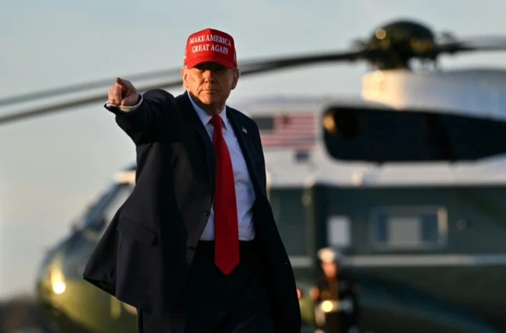 Le président américain Donald Trump fait signe de la main à une équipe de télévision au moment de monter à bord d'Air Force One, à la base Andrews près de Washington, le 28 février 2025