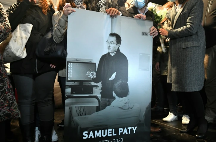 Des collègues et proches tiennent un portrait du professeur Samuel Paty lors d'une marche blanche à Conflans-Sainte-Honorine, le 20 octobre 2020