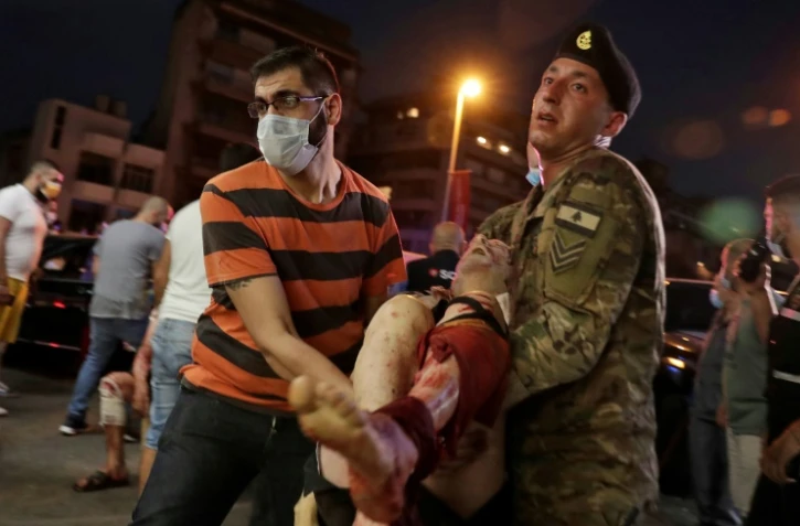 Un soldat libanais et un homme transportent un blessé à l'hôpital après les explosions le 4 août 2020