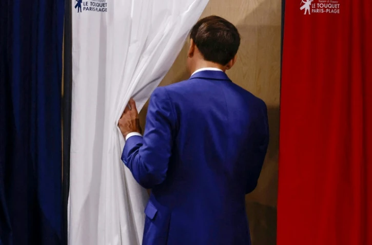 Le président Emmanuel Macron entre dans l'isoloir pour voter au premier tour des élections législatives dans un bureau de vote du Touquet, dans le Pas-de-Calais, le 30 juin 2024