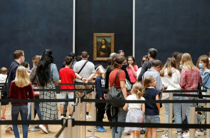 Des visiteurs protégés par des masques devant "Mona Lisa", le tableau de Léonard de Vinci dans une des salles du musée du Louvre, le 6 juillet 2020