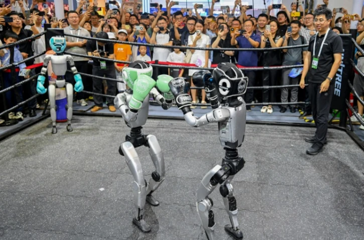 Des visiteurs regardent un combat de boxe entre robots lors de la World AI Conference (WAIC), le 26 juillet 2025 à Shanghai   