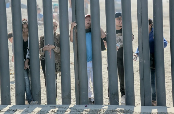 Des candidats à l'immigration aux Etats-Unis, venus du Honduras, regardent à travers le mur frontalier à San Ysidro (Californie)