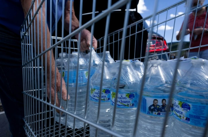 Un homme met des bouteilles d'eau dans sa voiture sur le parking d'un supermarché à Gérardmer dans l'est de la France, le 3 août 2022