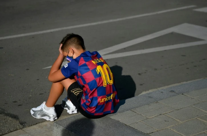 Un garçon avec le maillot de Lionel Messi attend le 30 août 2020 devant le centre d'entraînement du FC Barcelone où les joueurs devaient venir pour un dépistage du Covid