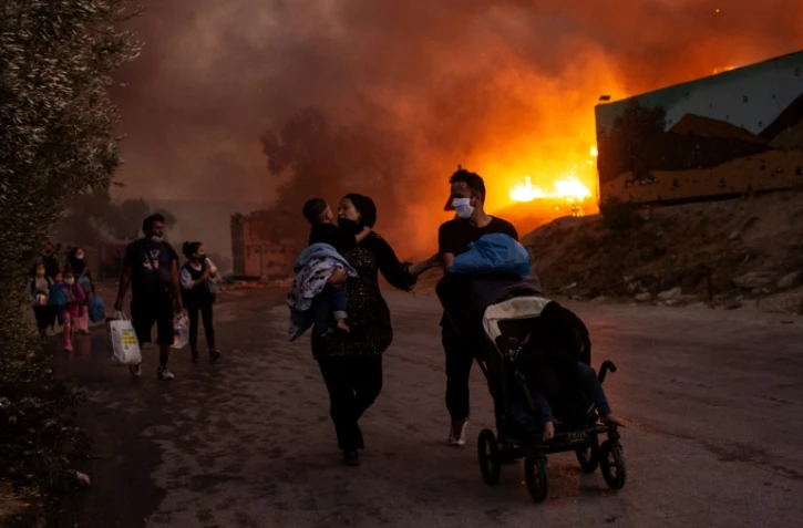 Une famille de migrants fuit le camp de Moria incendié, le 9 septembre 2020 à Lesbos, en Grèce