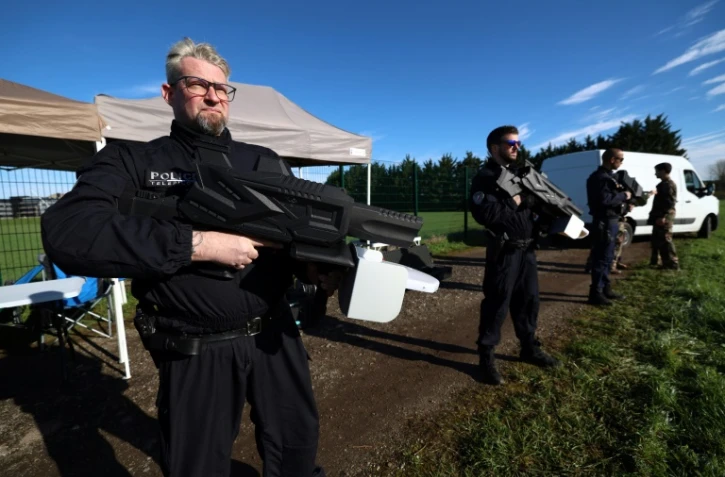 Des policiers français tiennent des fusils brouilleurs utilisés pour la lutte antidrones le 14 mars 2024 sur la base aérienne de Villacoublay