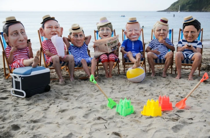 Des militants avec des masques à l'effigie des dirigeants du G7 lors d'une action menée par Oxfam, à Falmouth, le 11 juin 2021