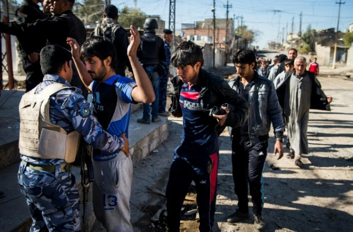 Un policier irakien contrôle des hommes à Mossoul le 18 novembre 2016