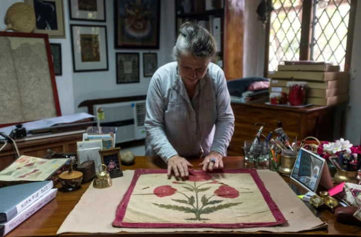 Brigitte Singh étend sur son bureau un carré d'étoffe moghol du XVIIe siècle, orné d'un grand pavot rouge, le 2 juin 2022 à Amber, dans l'Etat du Rajasthan, en Inde
