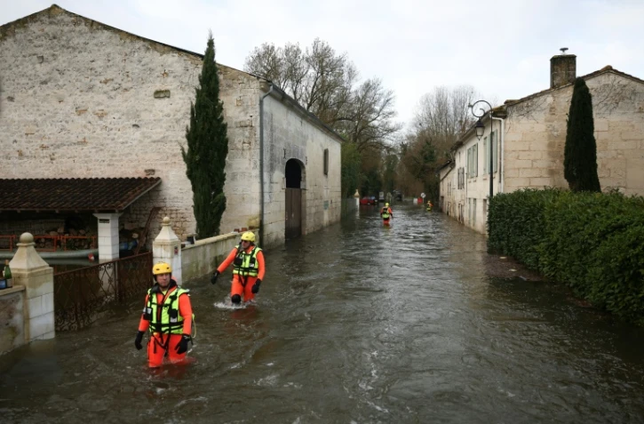 Des sauveteurs en mer dans une rue inondée lors d'une opération visant à évacuer des habitants isolés à Courcoury, en Charente-Maritime, le 21 février 2026