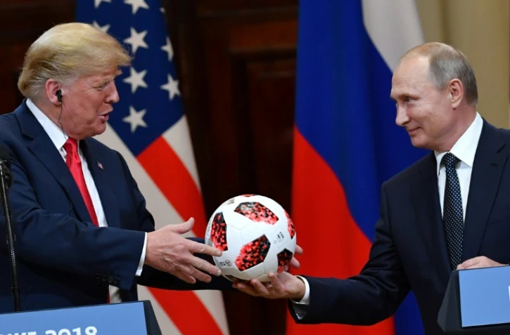 Le président russe Vladimir Poutine offre un ballon du Mondial au président américain Donald Trump, lors d'une conférence de presse commune, le 16 juillet 2018 à Helsinki   